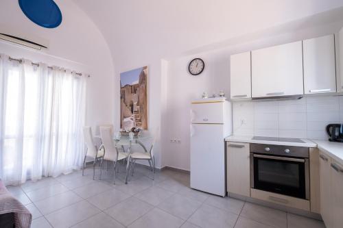 a kitchen with white appliances and a table with chairs at Adelphi Apartments in Perissa