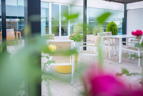 a patio with white chairs and tables and flowers at Hotel Xon's Valencia in Aldaya