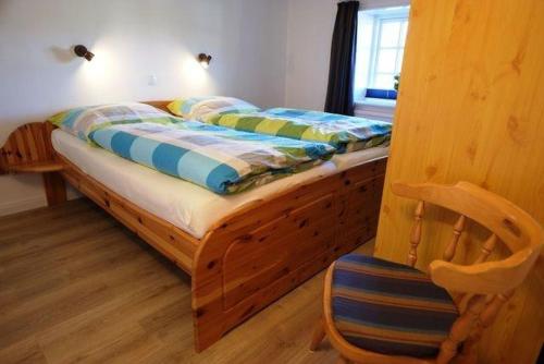a bed with a wooden frame in a room at Aarnhof-Wohnung-Schwalbe in Archsum