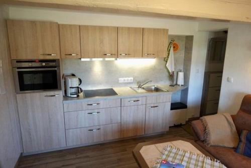 uma cozinha com armários de madeira e uma sala de estar em Aarnhof-Wohnung-Schwalbe em Archsum