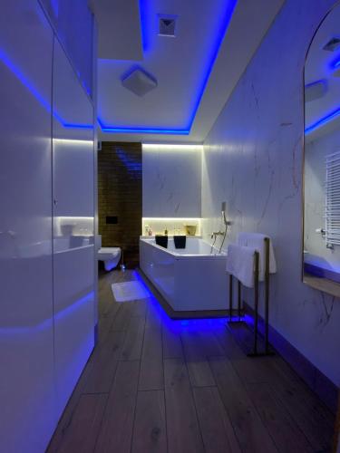 une salle de bain avec une baignoire blanche et des lumières bleues dans l'établissement Apartament "Love" Centrum z dużą wanną dla Dwojga, à Gniezno