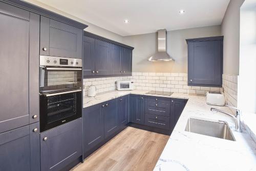 a kitchen with blue cabinets and a sink at Host & Stay - The Old Fireman's House in Saltburn-by-the-Sea