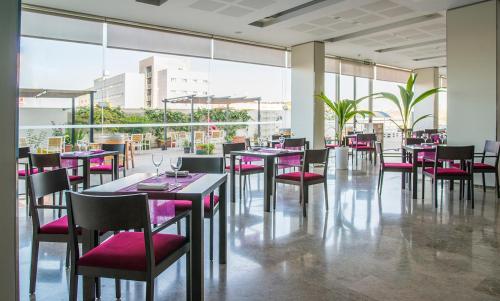 ein Restaurant mit rosa Stühlen, Tischen und Fenstern in der Unterkunft Hotel Xon's Valencia in Aldaia