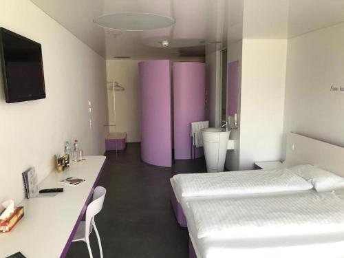a room with two beds and a desk and purple walls at Chromotel self check-in in Mezzovico