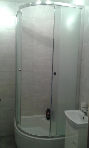 una ducha con una puerta de cristal junto a un lavabo en Kawalerka 1 km od morza Beautiful flat near the see, en Gdansk