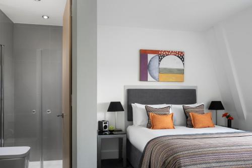 a bedroom with a large bed with orange pillows at Templeton Place by Supercity Aparthotels in London