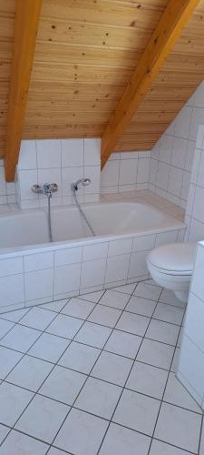 a white bathroom with a tub and a toilet at B&B Talstation Ferienwohnung für 2 Personen in Hörselberg-Hainich