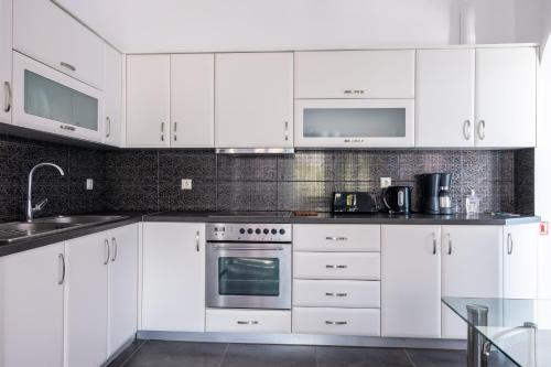 a white kitchen with white cabinets and appliances at Adelphi Apartments in Perissa