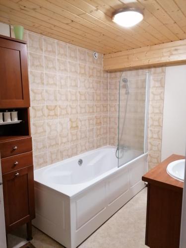 une salle de bain avec une baignoire et un lavabo dans l'établissement Chalet- Capacité 8/10 pers au cœur de la station, à Besse-et-Saint-Anastaise
