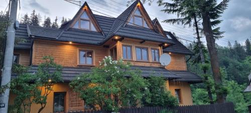 een houten huis met een zwart dak bij Willa Zacisze in Zakopane