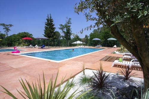 ein großer Pool mit Stühlen und Sonnenschirmen in der Unterkunft La Bastide in Mazères