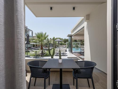 un tavolo e sedie su un balcone con vista sulla piscina di Mossa Well Being Hotel a Kato Daratso