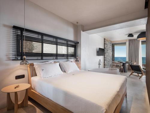 um quarto com uma grande cama branca e uma mesa em Brand new Luxury Seannamon Suites, amazing seaview em Agios Nikolaos