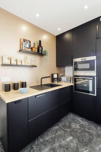 a kitchen with black cabinets and a sink at L'Anjépie in Passenans
