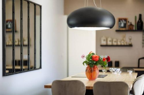 a dining room table with a vase of flowers and a lamp at L'Anjépie in Passenans