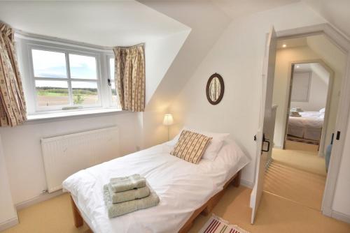 a small bedroom with a white bed and a window at Gardener's Cottage in Elgin