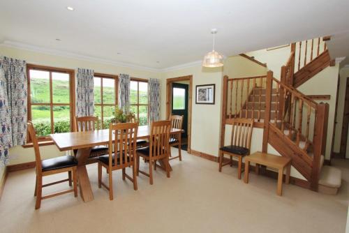 a dining room with a table and chairs and a staircase at Saltwinds in Carbost