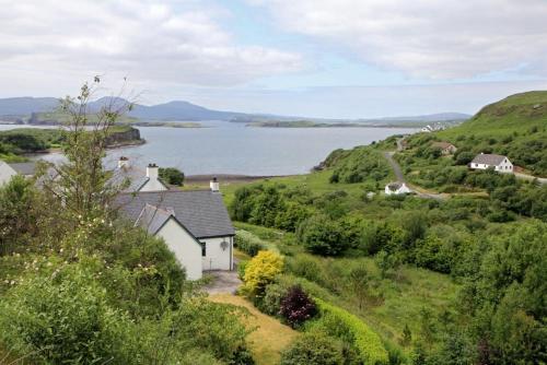 a house on a hill next to a body of water at Saltwinds in Carbost