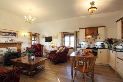 cocina y sala de estar con mesa y sillas en Smiddy Cottage, en Pollachar