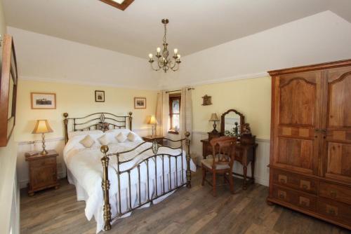 a bedroom with a bed and a dresser and a chandelier at Smiddy Cottage in Pollachar