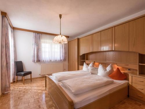 - une chambre avec un grand lit et une chaise dans l'établissement Appartement Melodie, à Scheffau am Wilden Kaiser