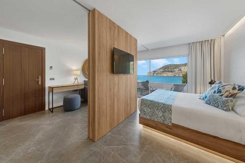 Habitación de hotel con cama y vistas al océano en Bahía Suites Camp de Mar en Camp de Mar