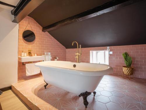 a large bathroom with a white tub and pink tiles at Unique Romantic Getaway in Thornton