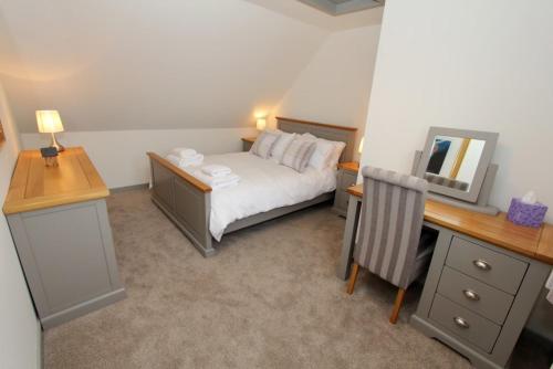 a bedroom with a bed and a desk with a mirror at Katie's Cottage in Amhuinnsuidhe