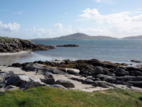 a beach with rocks and the water and a mountain at Conan Mara in Eriskay