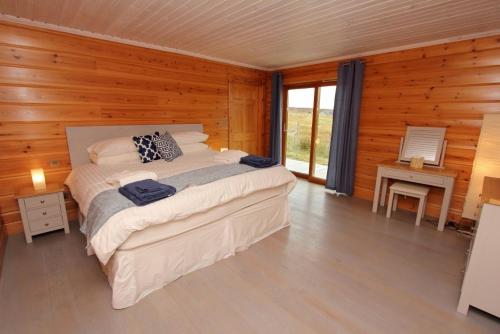 a bedroom with a bed in a wooden room at Eagle Lodge in Stornoway