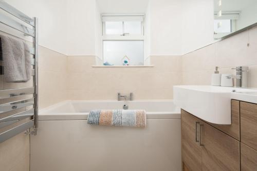a white bathroom with a tub and a sink at Gaidrew Cottage in Drymen