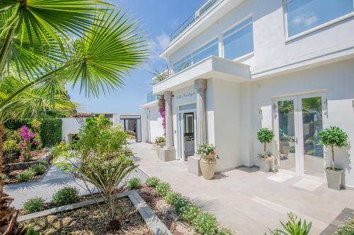 une maison blanche avec des plantes et un palmier dans l'établissement Villa Sandryon, à Antibes