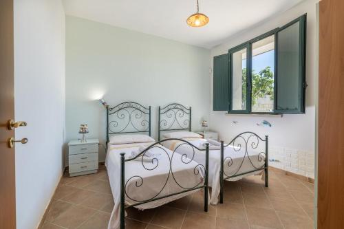 1 dormitorio con 2 camas y ventana en Villa Campagnola, en Carpignano Salentino