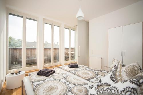 a white bedroom with a large bed and windows at Kokon Apartments in Leipzig