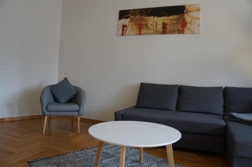 ein Wohnzimmer mit einem Sofa, einem Tisch und einem Stuhl in der Unterkunft Kokon Apartments in Leipzig