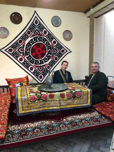 two men sitting on a bed with a rug at Hotel Han in Samarkand