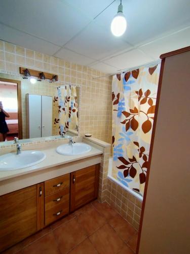 a bathroom with two sinks and a shower curtain at En la gloria. in Peniscola