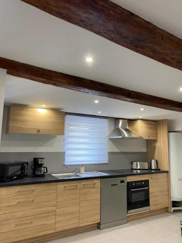 une cuisine avec des placards en bois et une fenêtre. dans l'établissement Maison individuelle à Chanac 2 Chambres 1 canapé lit Wifi Gratuit, à Chanac