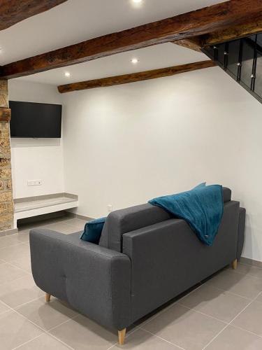 - un canapé gris dans un salon avec un mur dans l'établissement Maison individuelle à Chanac 2 Chambres 1 canapé lit Wifi Gratuit, à Chanac