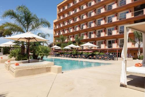 a hotel pool with chairs and umbrellas and a hotel at Luna Club Hotel Yoga & Spa 4Sup in Malgrat de Mar