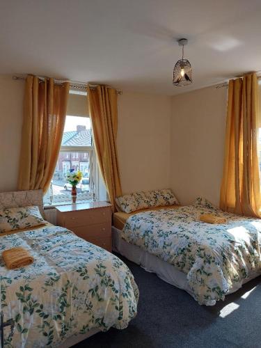 um quarto com 2 camas e uma janela em The Cosy 2 bedroom flat, sleeps 6 em Hebburn-on-Tyne