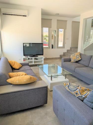 a living room with two couches and a tv at T&E Villa in Larnaka