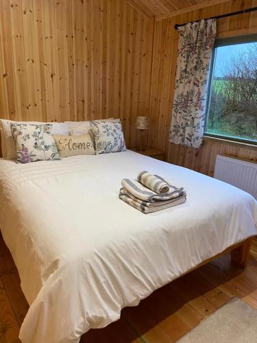 a bedroom with a bed with towels on it at Rural Wood Cabin - less than 3 miles from St Ives in Penzance