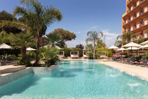 a swimming pool in a hotel with chairs and a building at Luna Park Hotel Yoga & Spa in Malgrat de Mar
