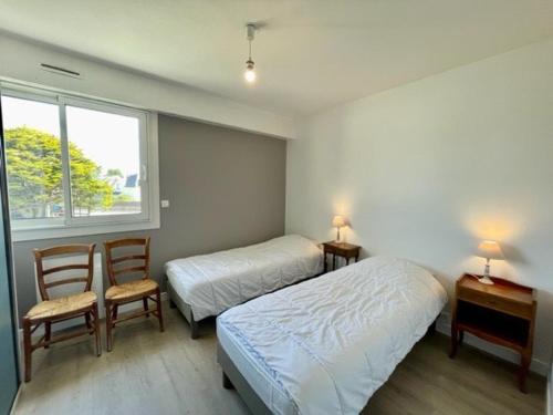 a bedroom with two beds and a table and two chairs at Quiberon - Grand T2 - Balcon Sud - 70m² - Plage & Centre - Parking & WIFI - FR-1-478-203 in Quiberon