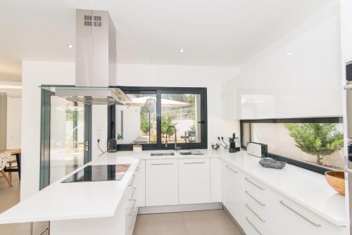 a kitchen with white cabinets and a large window at Villa 91 by ALGARTUR in Tavira
