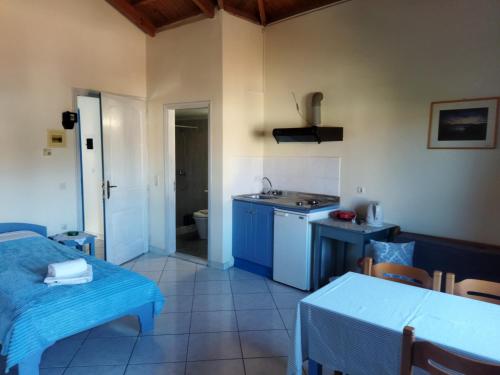 uma cozinha com armários azuis, uma mesa e um lavatório em Roxani Studios-Apartments em Petra