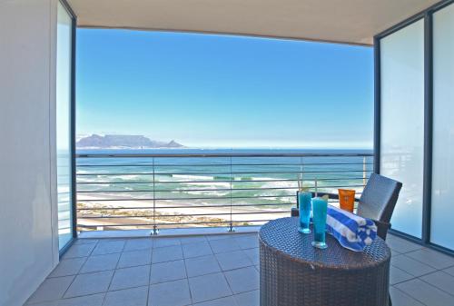 a table with a glass of water and a laptop on it at Blaauwberg Beach Hotel in Bloubergstrand