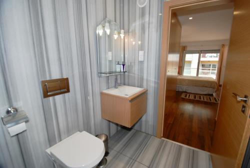 a bathroom with a toilet and a sink and a mirror at Whale - Apartment with Wi-Fi and heated pool in São Martinho do Porto