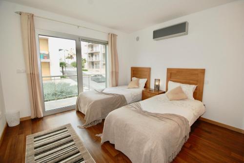 um quarto com 2 camas e uma grande janela em Whale - Apartment with Wi-Fi and heated pool em São Martinho do Porto